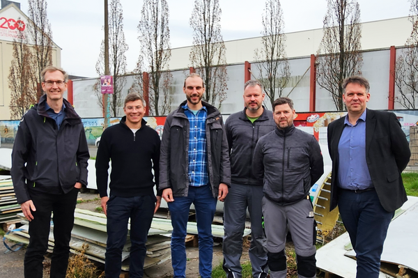 Gruppenfoto, im Hintergrund zerlegte Rotorblätter zu sehen
