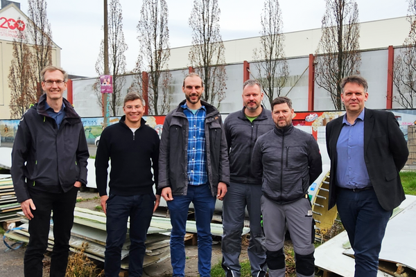 Gruppenfoto, im Hintergrund zerlegte Rotorblätter zu sehen